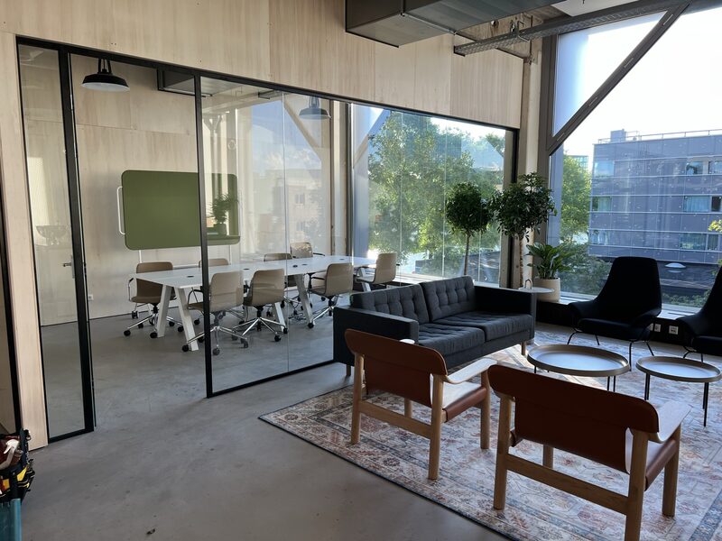 Lichte kantoorlounge met glazen wanden en groot raam, gebouwd op het Marineterrein in Amsterdam